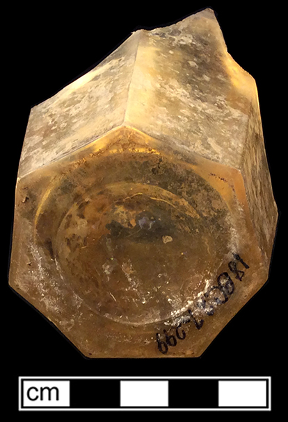 Colorless leaded glass panelled tumbler.  7-sided base. 3” height; 3.5” rim diameter; 2.25” base diameter (widest point). The yellowish color to this vessel is believed to be caused by post-depositional factors. 18BC27-F30